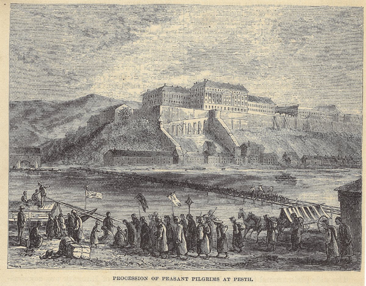 Wood engraving: the long Royal Palace on Castle Hill at Buda seen across the Danube, with a column of peasant pilgrims carrying banners moving along the Pest bank in the foreground toward a bridge of boats that runs out across the river; a tented cart, a horse, and seated figures at the right.